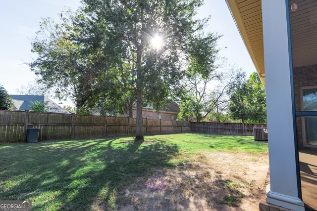 a view of a backyard with a large tree and wooden fence