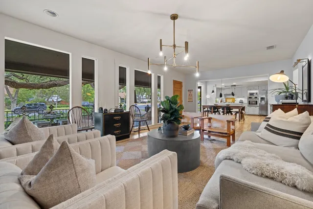 a living room with furniture kitchen view and large windows
