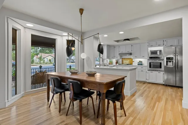 a kitchen with stainless steel appliances kitchen island granite countertop a table chairs and a wooden floor