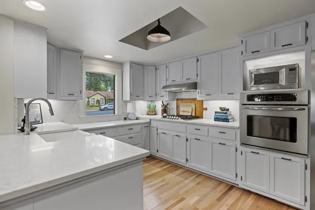 a kitchen with granite countertop white cabinets and a stove top oven