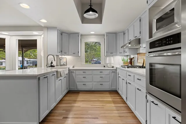 a kitchen with white cabinets stainless steel appliances and a window
