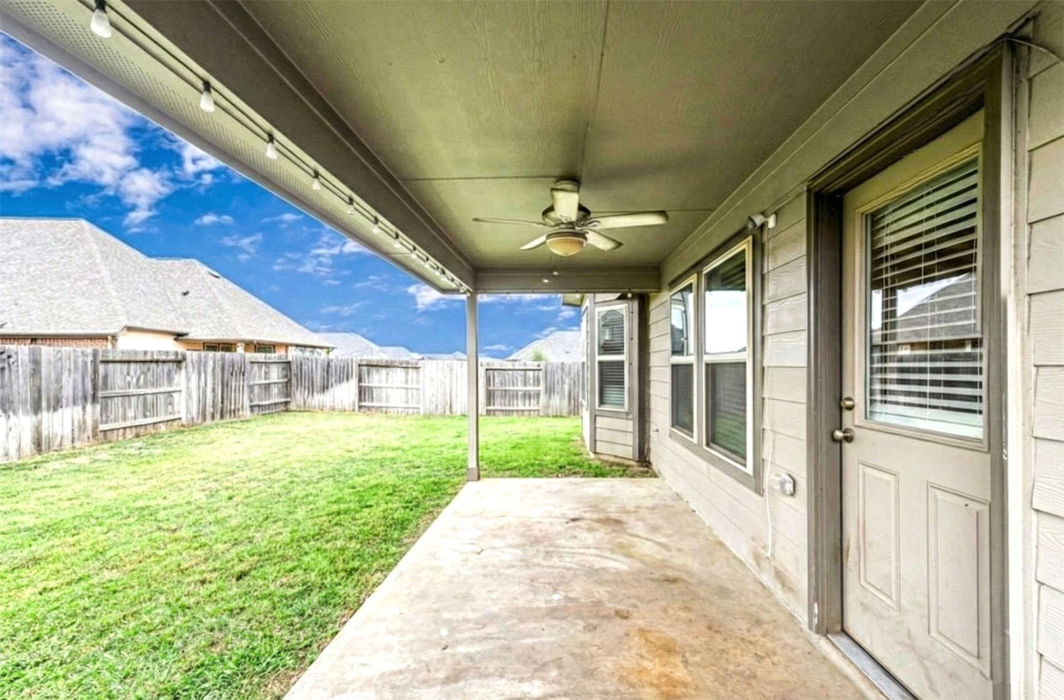 17439 Chester Valley Trail Hockley, TX 77447 - Photo 16 of 22 This photo showcases a covered patio with a ceiling fan, offering a view of a spacious fenced backyard, perfect for outdoor relaxation and activities.