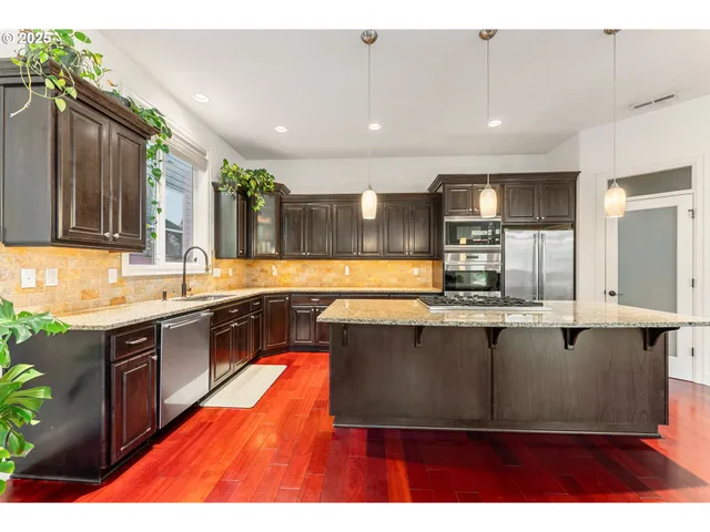 a large kitchen with kitchen island a sink wooden floor and stainless steel appliances