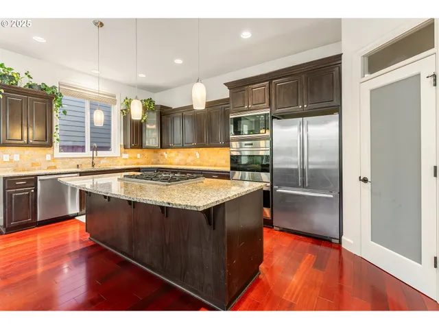 a kitchen with stainless steel appliances granite countertop a sink and a refrigerator