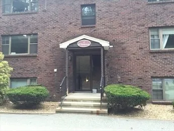 a view of a brick house with potted plants and a table and chair