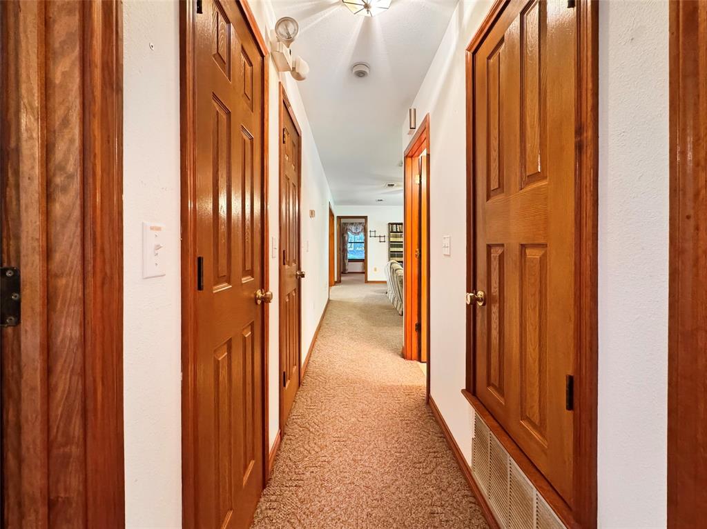 3870 County Road Arthur City, TX 75411 - Photo 21 of 39 Hallway with textured carpeting, white walls, and multiple paneled wood doors