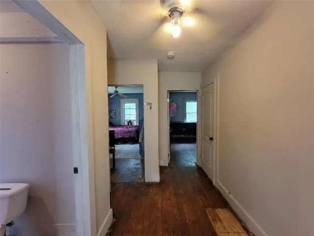 a view of a hallway with wooden floor and a bathroom