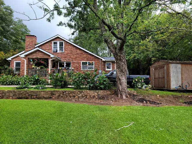 a view of a house with a big yard and large trees