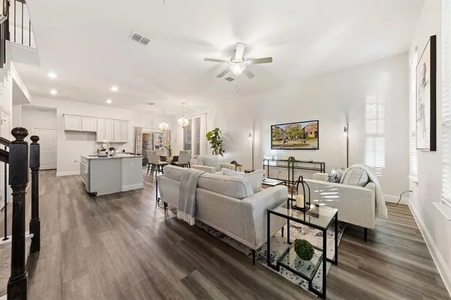 a living room with couches and kitchen view with wooden floor