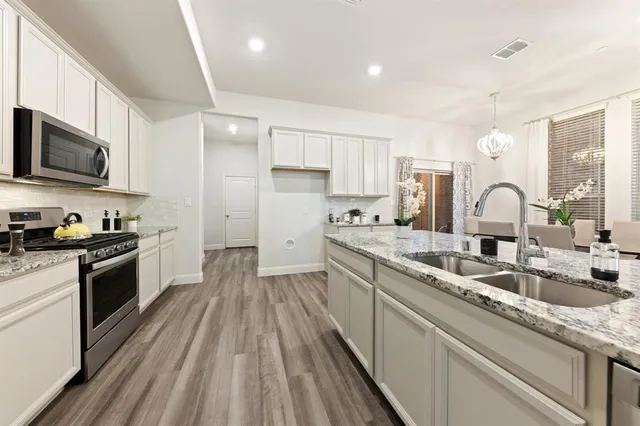 a kitchen with granite countertop a sink wooden floor and stainless steel appliances