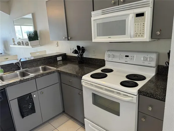 a kitchen with granite countertop a sink a stove and cabinets