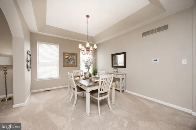 a view of a dining room and livingroom with furniture wooden floor a chandelier