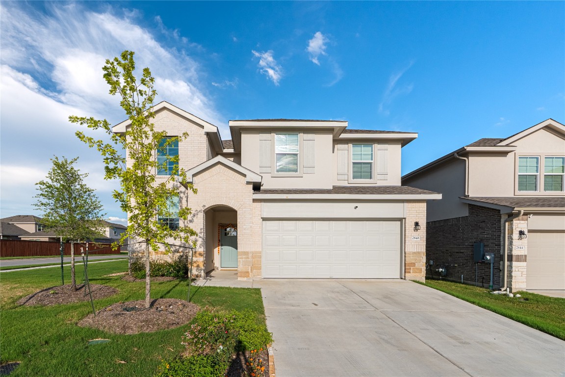 View of front of property featuring a garage, concrete driveway, brick siding, and a front yard