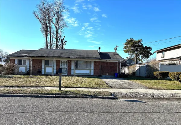 a front view of a house with a garden and tree