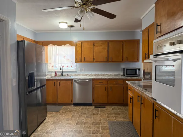 a kitchen with stainless steel appliances granite countertop a refrigerator a sink dishwasher a stove and a microwave