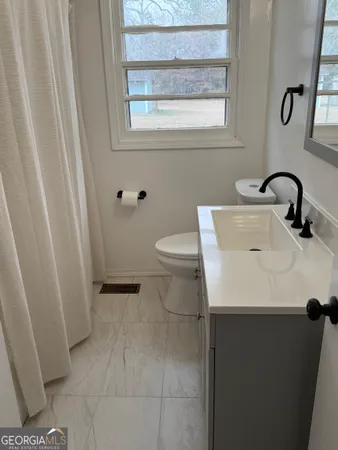 a bathroom with a sink a toilet and a window