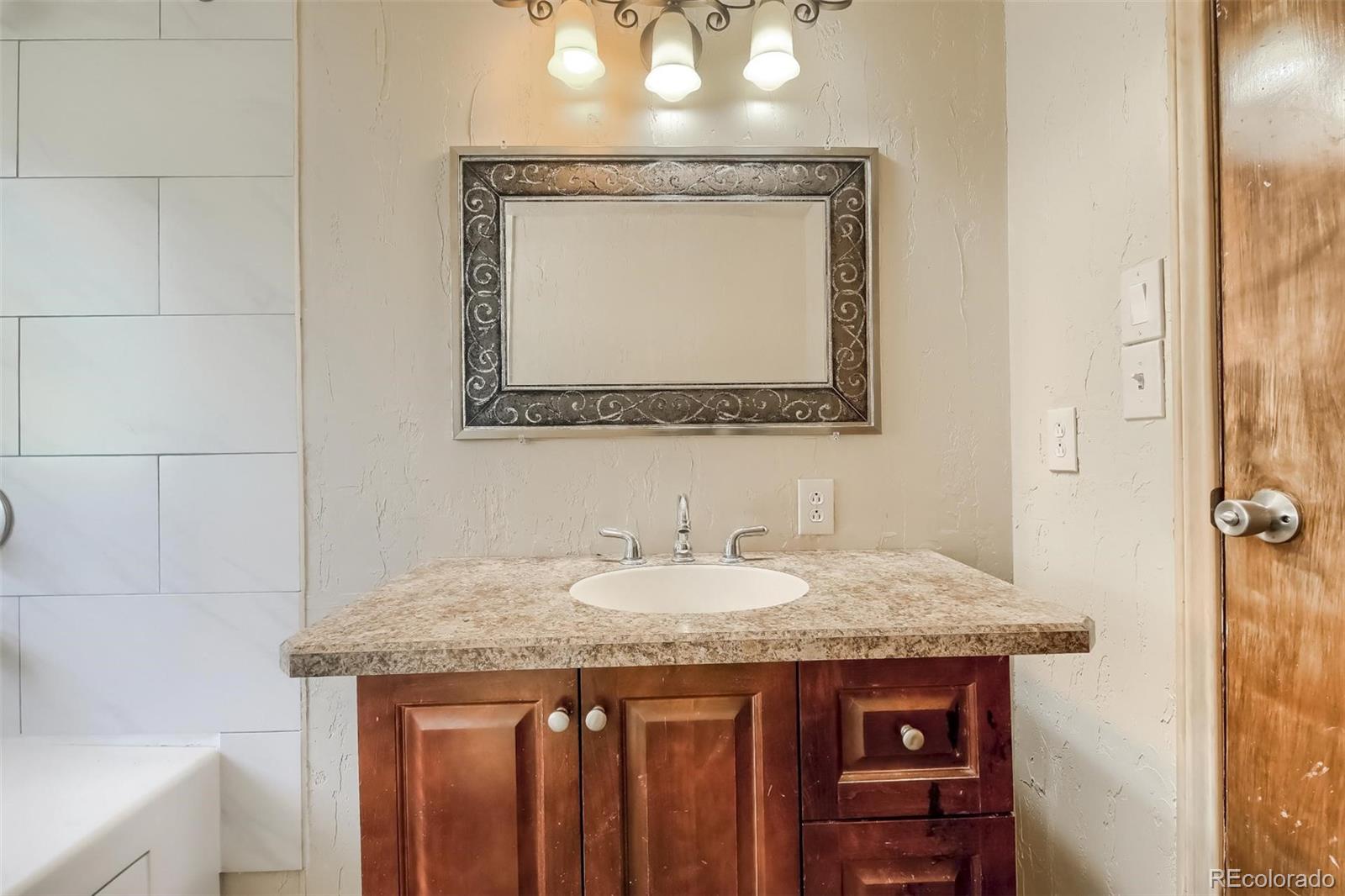 145 Bailey Drive Bailey, CO 80421 - Photo 17 of 40 a bathroom with a granite countertop sink a mirror and a vanity
