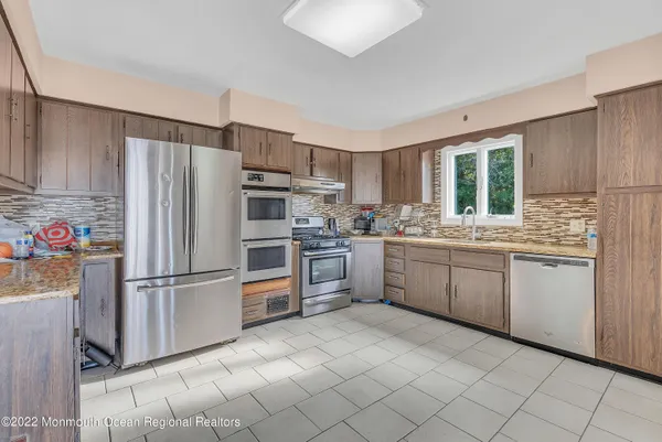 a kitchen with white cabinets stainless steel appliances and a window