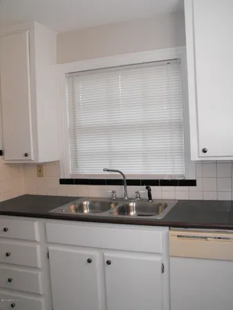 a kitchen with granite countertop white cabinets and a sink