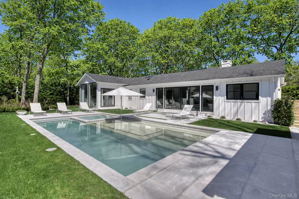 a view of house with a swimming pool and a yard