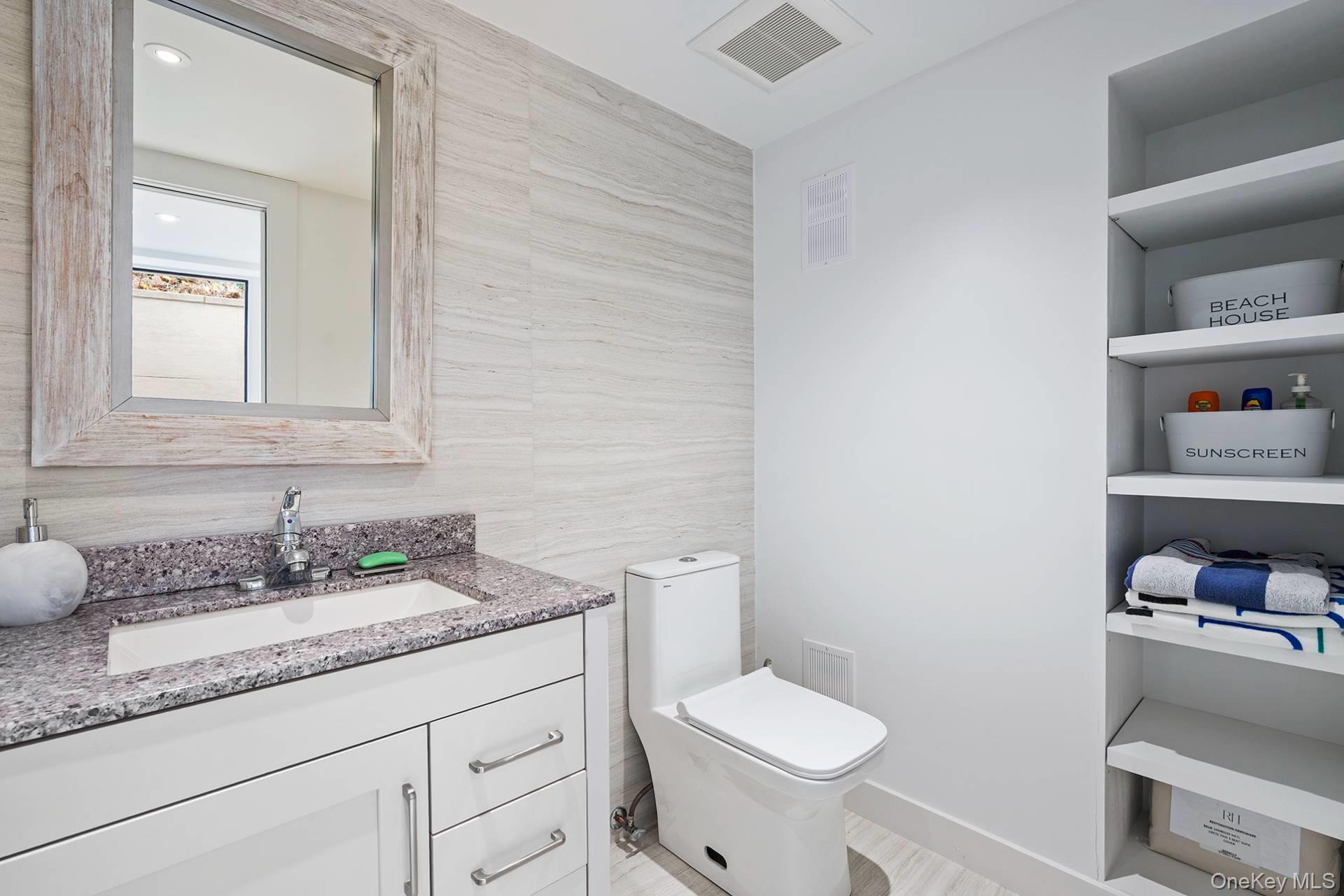 54 Glade Road East Hampton, NY 11937 - Photo 34 of 35 a bathroom with a granite countertop sink a toilet and a mirror