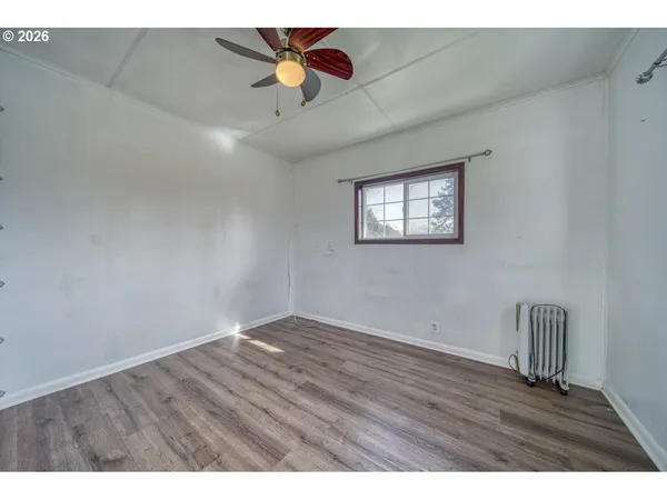 an empty room with wooden floor chandelier fan and windows