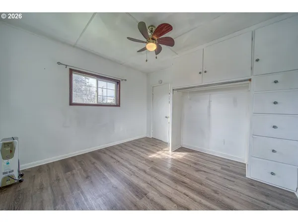 a view of an empty room with cabinet and wooden floor