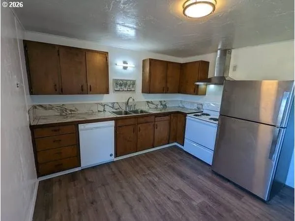 a kitchen with stainless steel appliances granite countertop wooden cabinets a refrigerator a sink and a stove