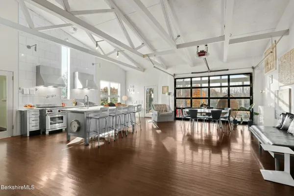 a living room with lots of furniture wooden floor and a large window
