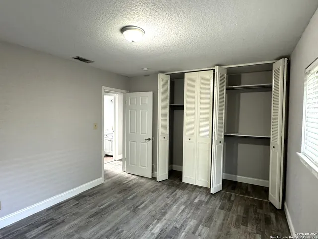 a view of an empty room with wooden floor and closet