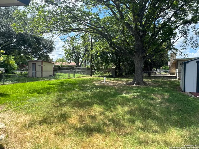 a backyard of a house with lots of plants and large tree
