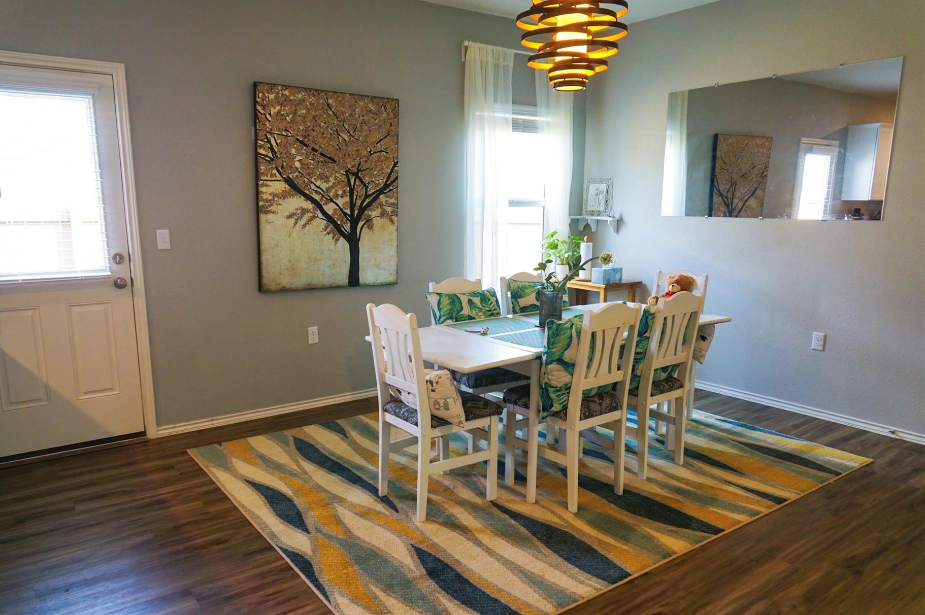 2321 Forgetmenot Lane Manor, TX 78653 - Photo 8 of 27 A vibrant area rug defines the dining space, set against durable wood flooring, illuminated by a distinctive chandelier.