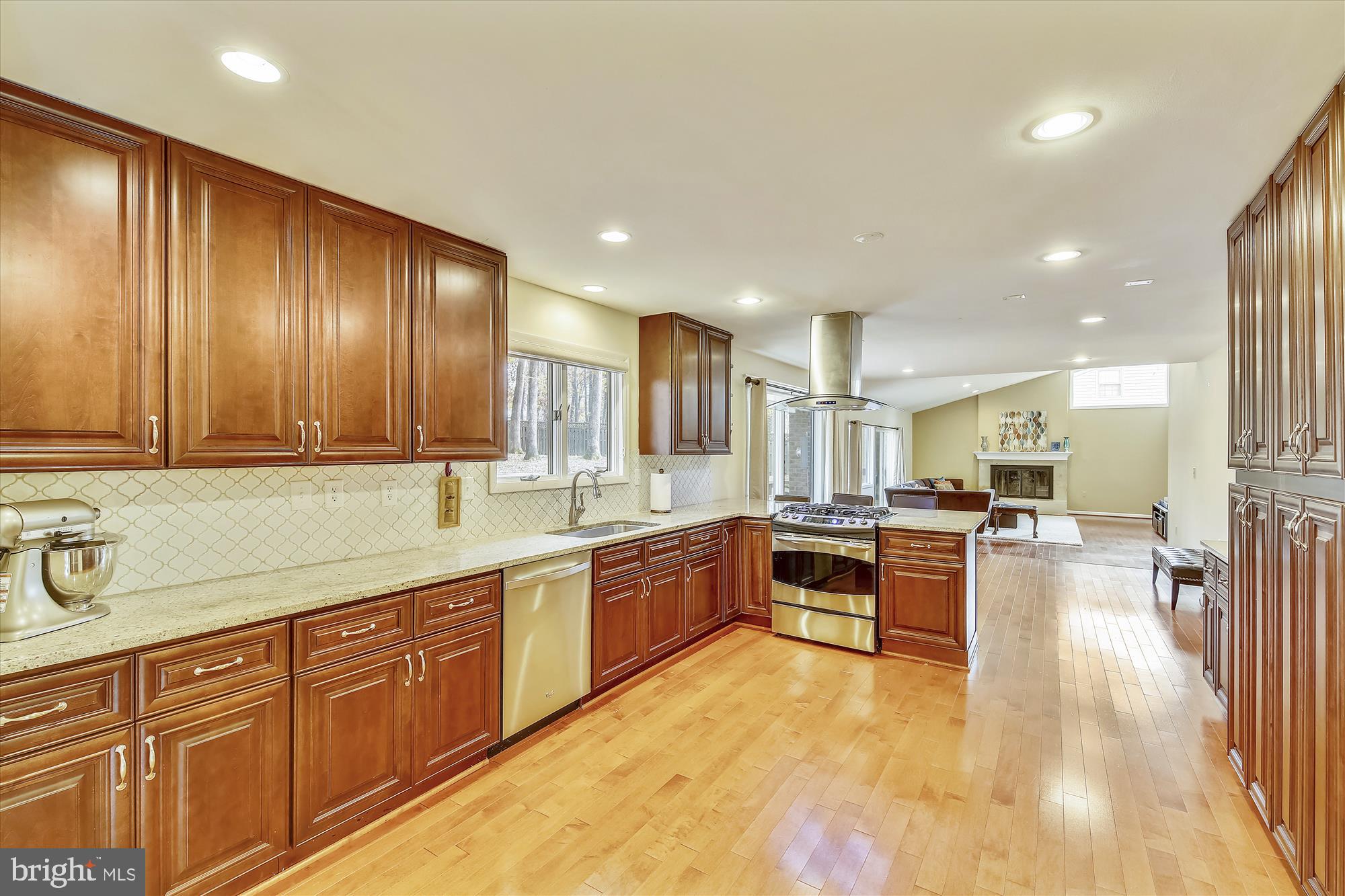 a large kitchen with stainless steel appliances wooden cabinets and a stove top oven