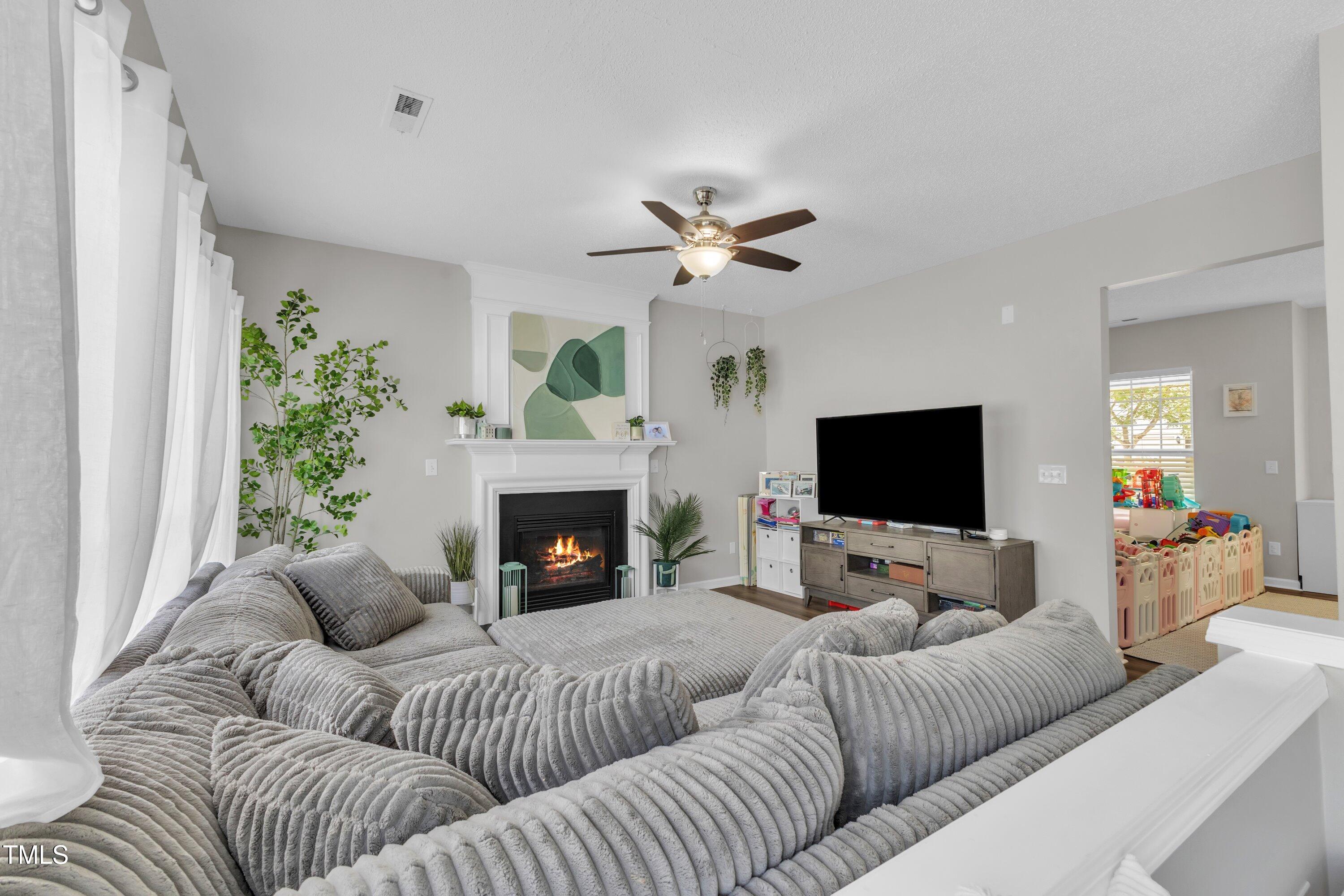 4105 Crowfield Drive Raleigh, NC 27610 - Photo 12 of 38 a living room with furniture a fireplace and a flat screen tv