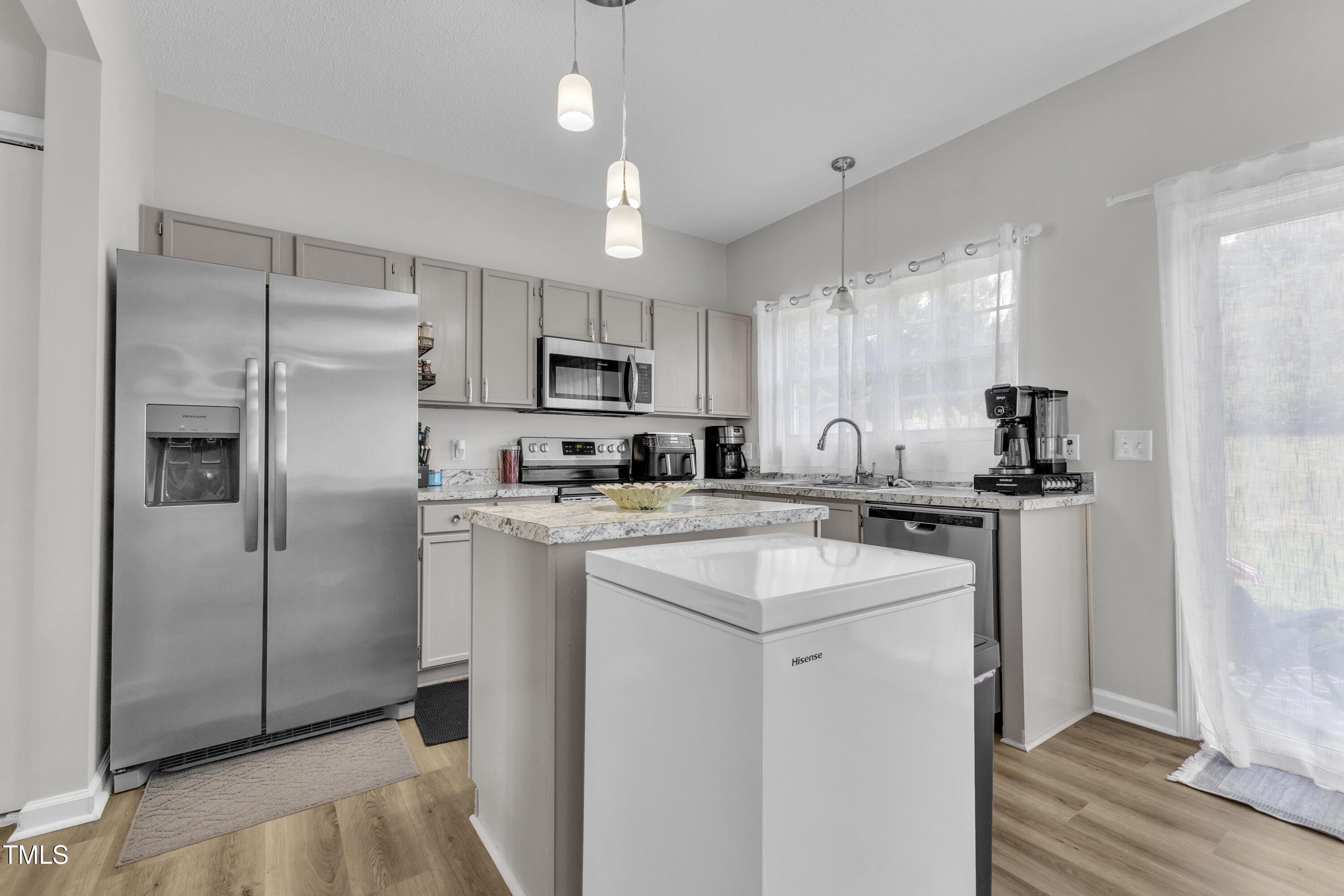 4105 Crowfield Drive Raleigh, NC 27610 - Photo 13 of 38 a kitchen with kitchen island a refrigerator sink and cabinets