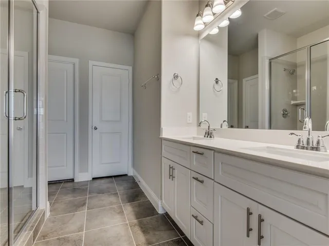a spacious bathroom with a double vanity sink a mirror and a shower