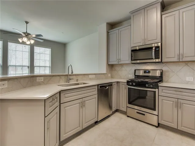 a kitchen with granite countertop white cabinets and stainless steel appliances