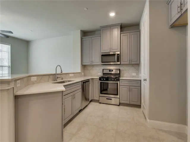 a kitchen with stainless steel appliances a sink stove and cabinets