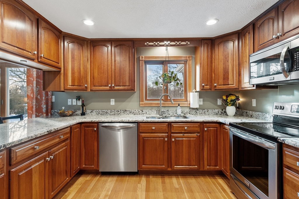 5 Spaulding Hill Road Pelham, NH 03076 - Photo 17 of 40 a kitchen with stainless steel appliances granite countertop wooden cabinets a sink and dishwasher a stove with wooden floor