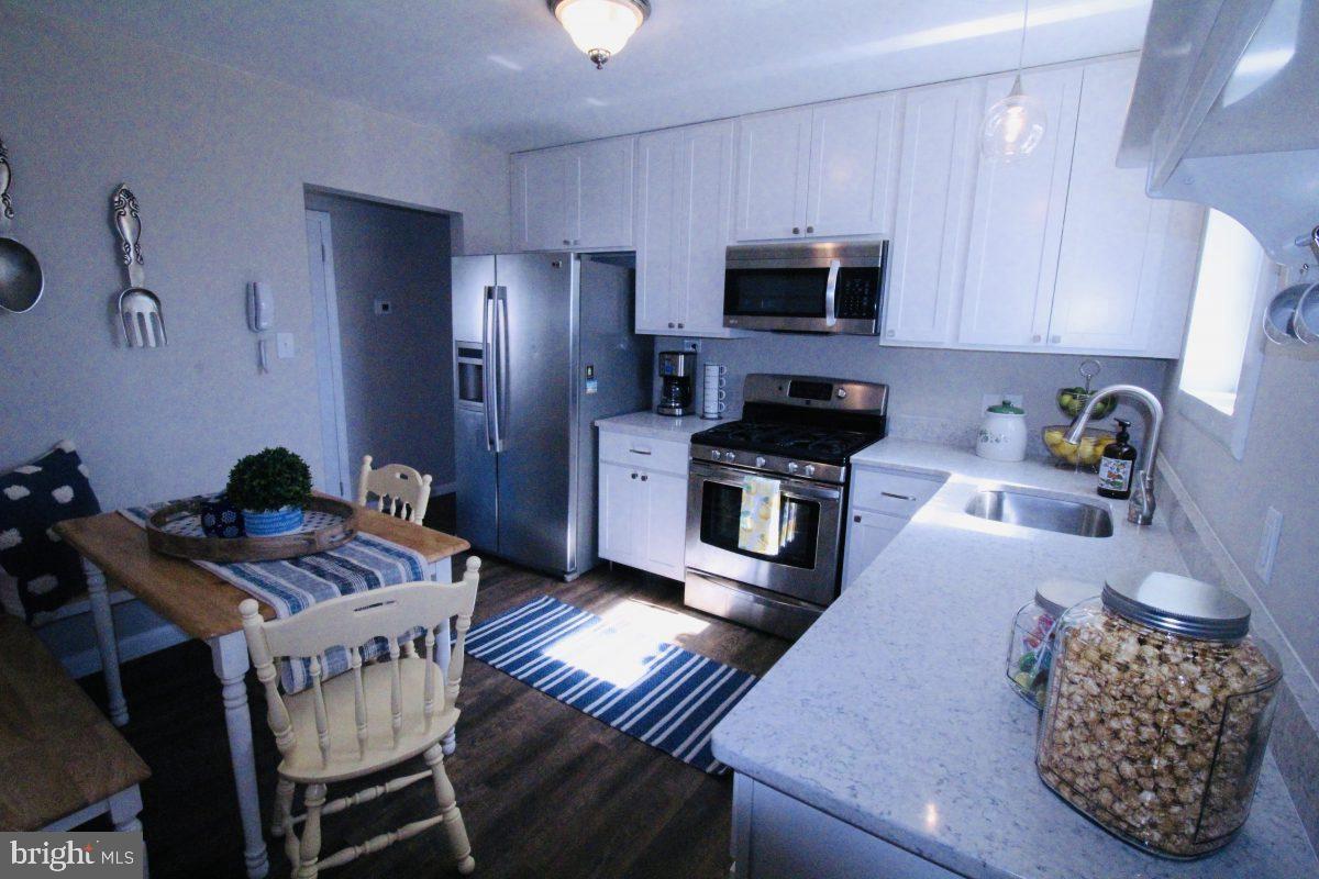 388 Nimitz Road Dover, DE 19901 - Photo 8 of 25 a kitchen with stainless steel appliances granite countertop a stove refrigerator a dining table and chairs with wooden floor