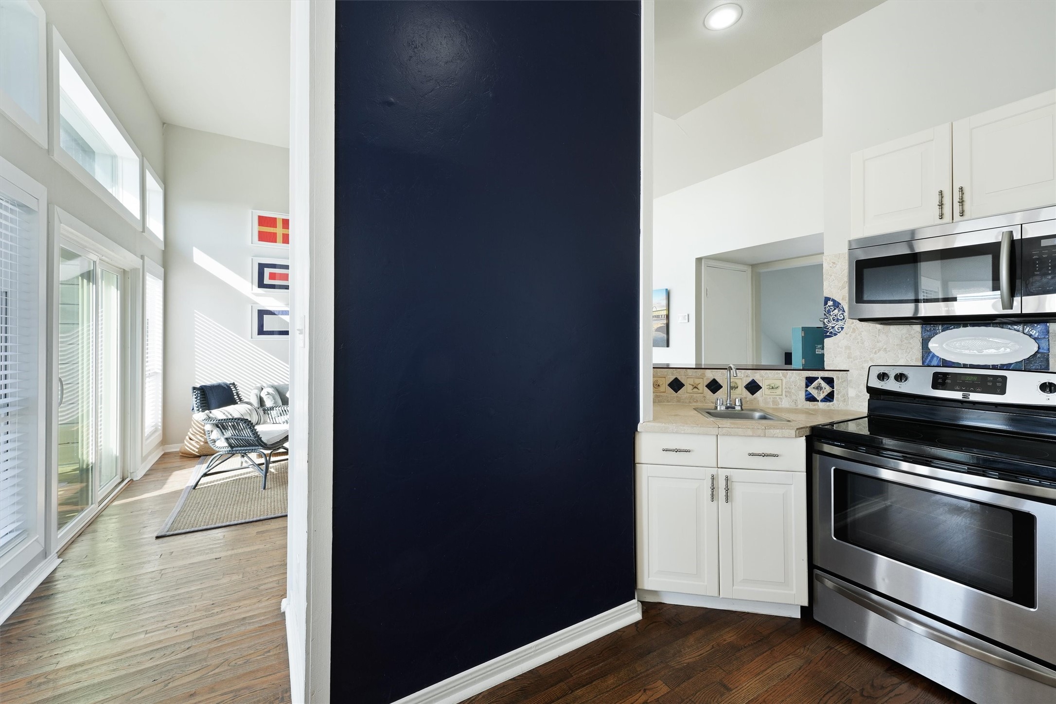 17607 Termini-San Luis Pass Road Galveston, TX 77554 - Photo 13 of 42 A navy accent wall gives the kitchen a bold touch that contrasts beautifully with the crisp white cabinetry. The cozy layout offers all the amenities needed for a comfortable cooking experience.