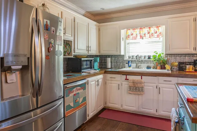 a kitchen with stainless steel appliances a dining table chairs and a refrigerator