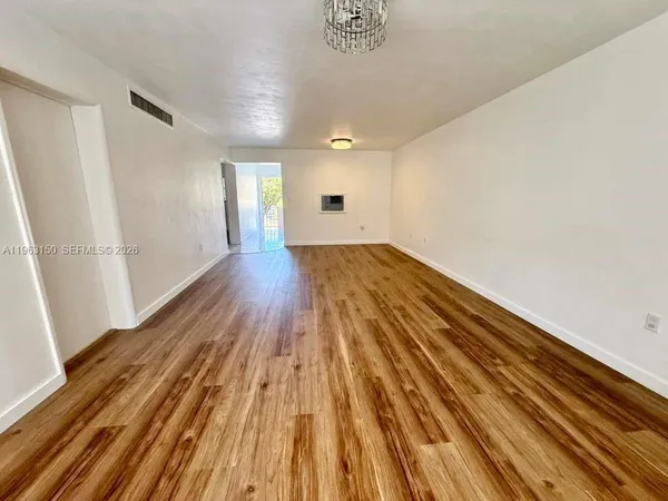 a view of empty room with wooden floor