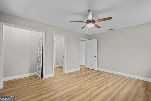 an empty room with wooden floor ceiling fan and windows