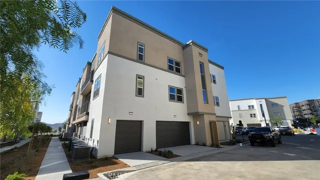 a view of a white building among the street with palm trees