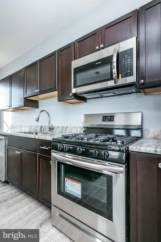 a kitchen with stainless steel appliances a stove a microwave cabinets and a wooden floor
