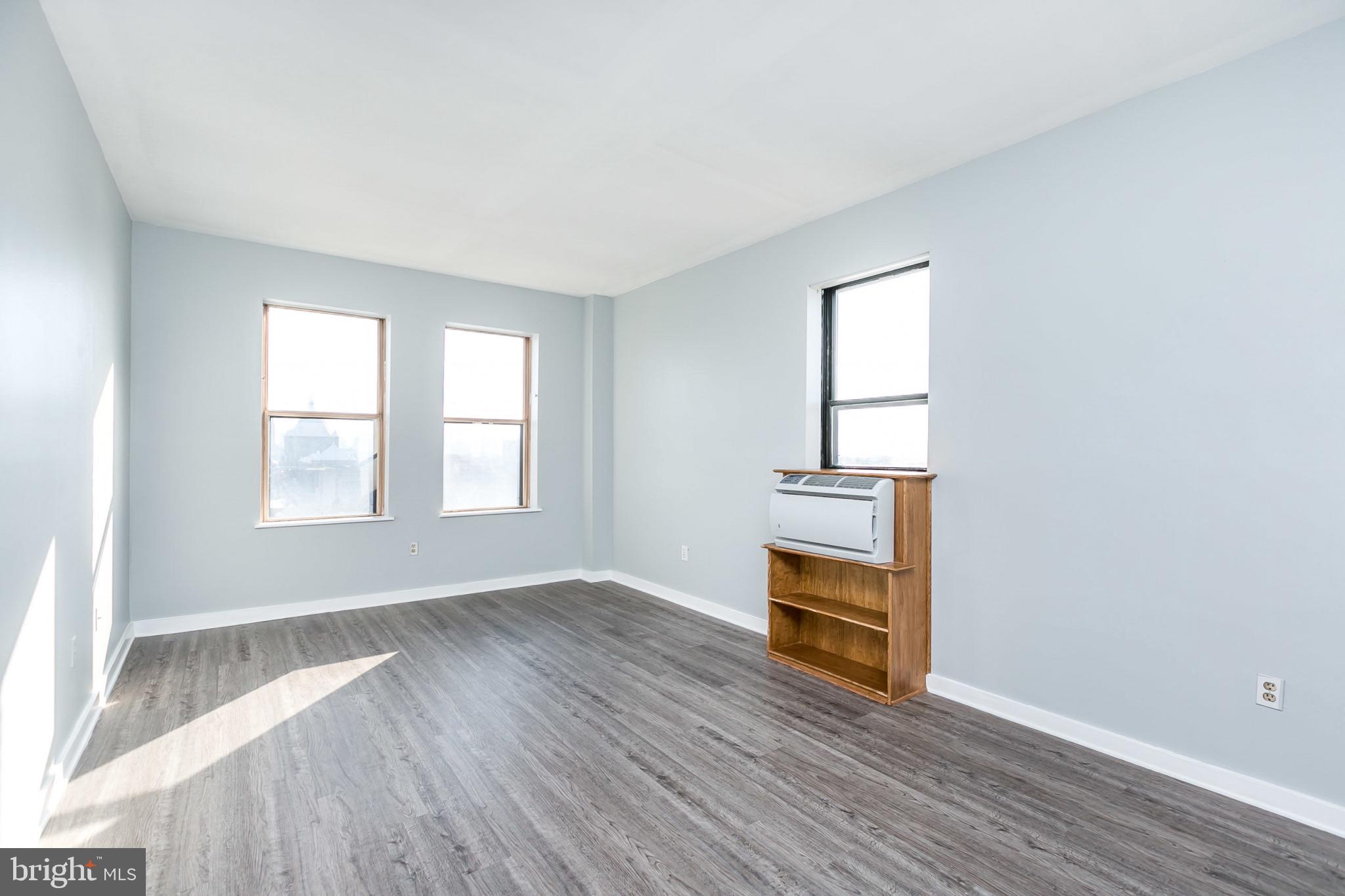 1001 St Paul Street, Unit 6G Baltimore, MD 21202 - Photo 3 of 32 an empty room with wooden floor staircase and windows