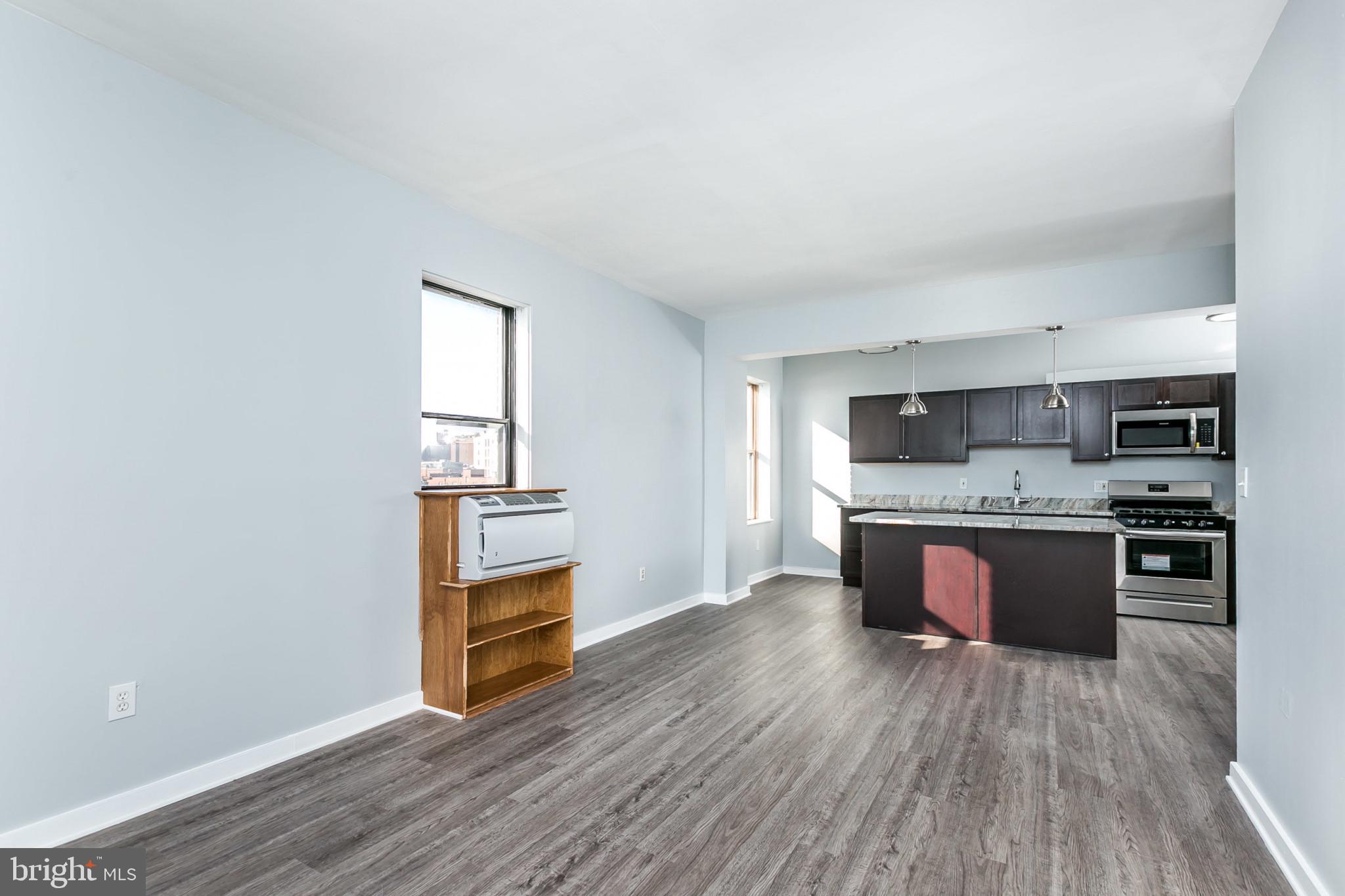 1001 St Paul Street, Unit 6G Baltimore, MD 21202 - Photo 5 of 32 a kitchen with stainless steel appliances wooden floors and wooden cabinets