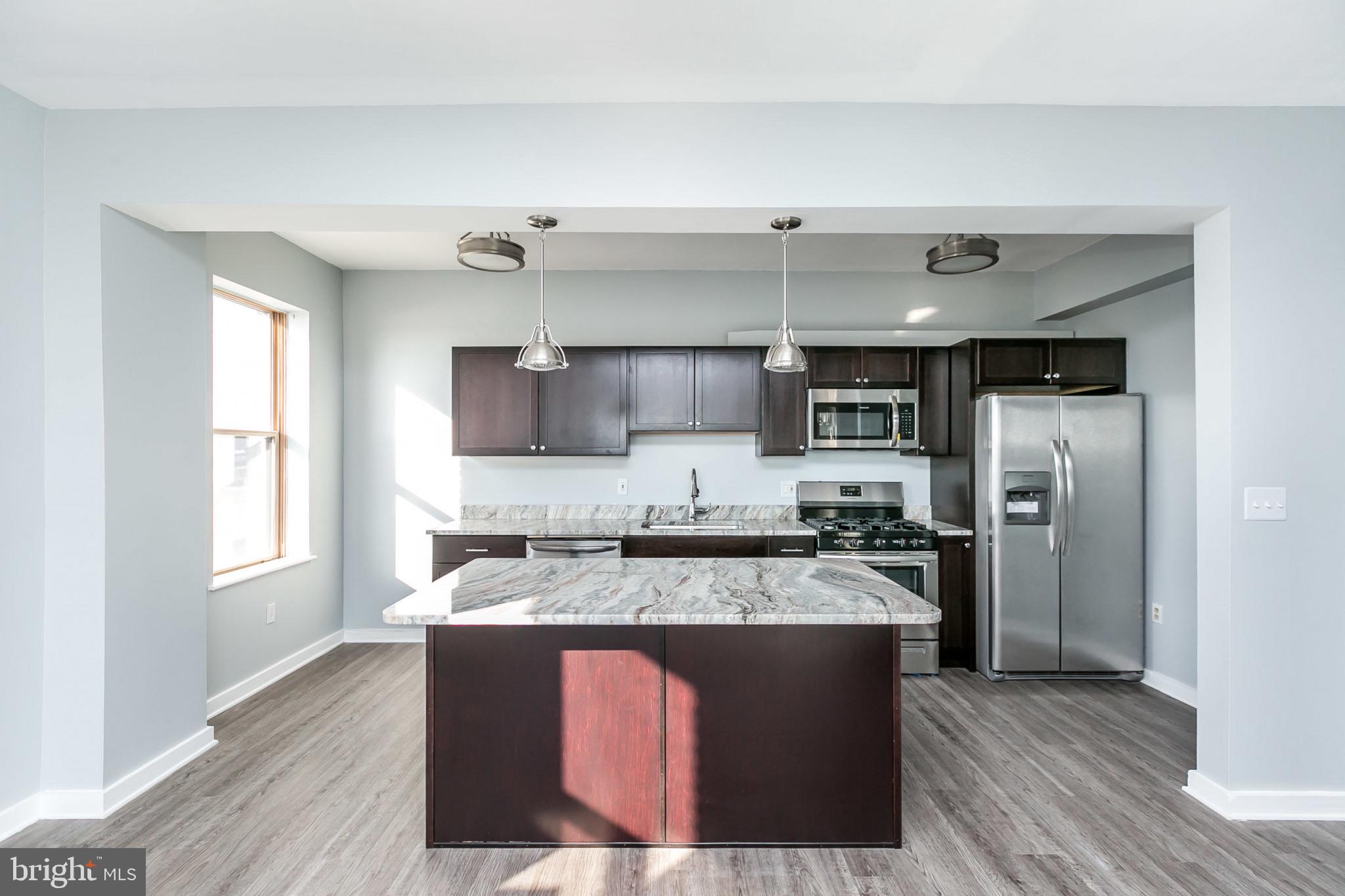 1001 St Paul Street, Unit 6G Baltimore, MD 21202 - Photo 7 of 32 a large kitchen with stainless steel appliances granite countertop a stove a sink and a refrigerator