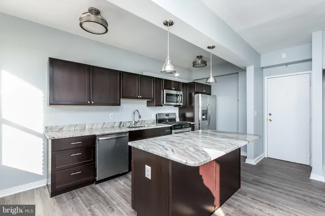 a kitchen with stainless steel appliances granite countertop a sink stove refrigerator granite counter tops wooden cabinets and wooden floor